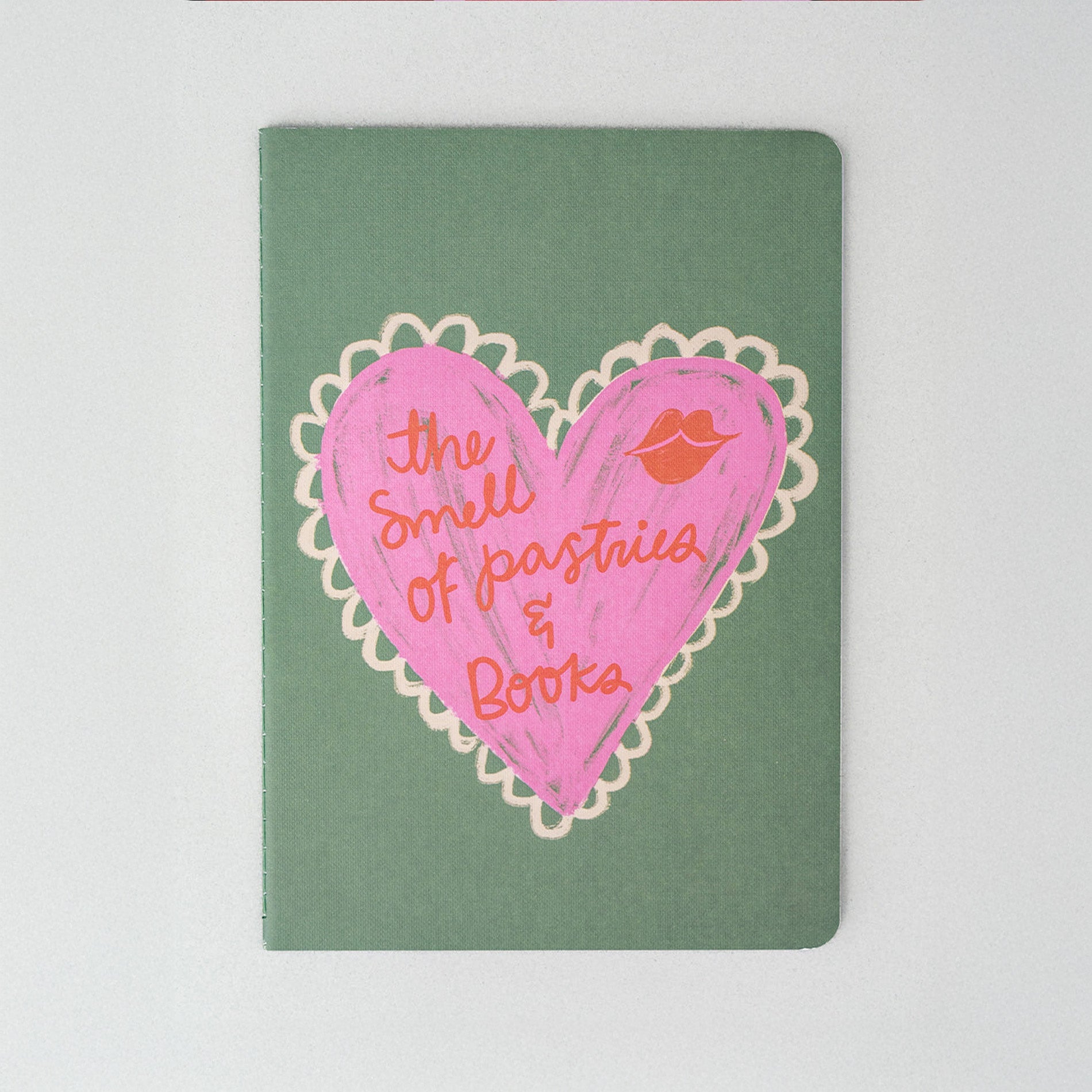 Notebook with pink heart design and text on a green background