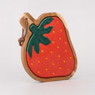 side view of Strawberry-shaped wooden trivet with a green leaf on a light gray background