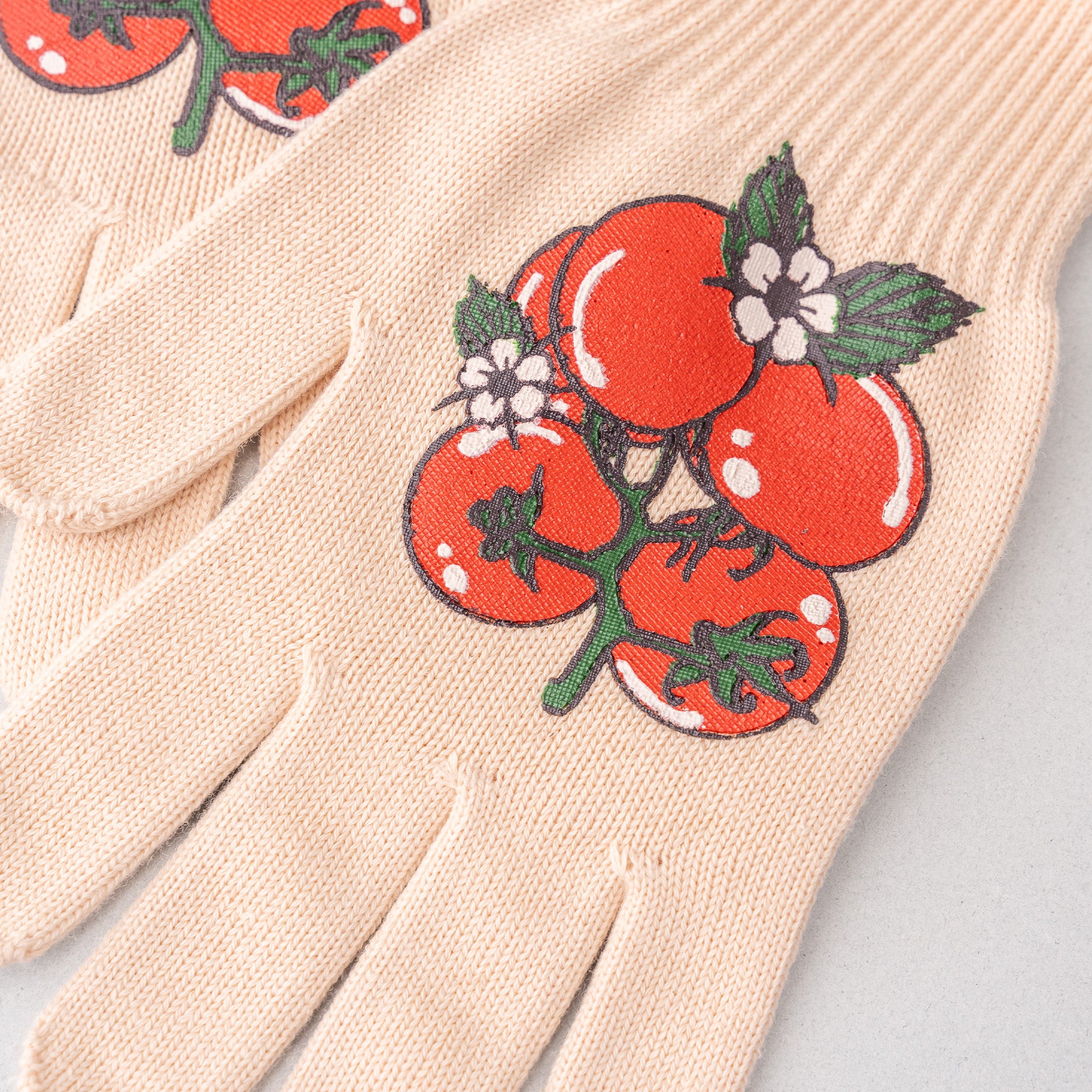 Beige gardening gloves with tomato design on a light gray background