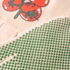 Close-up of green bead pattern on fabric with tomato illustration in the background