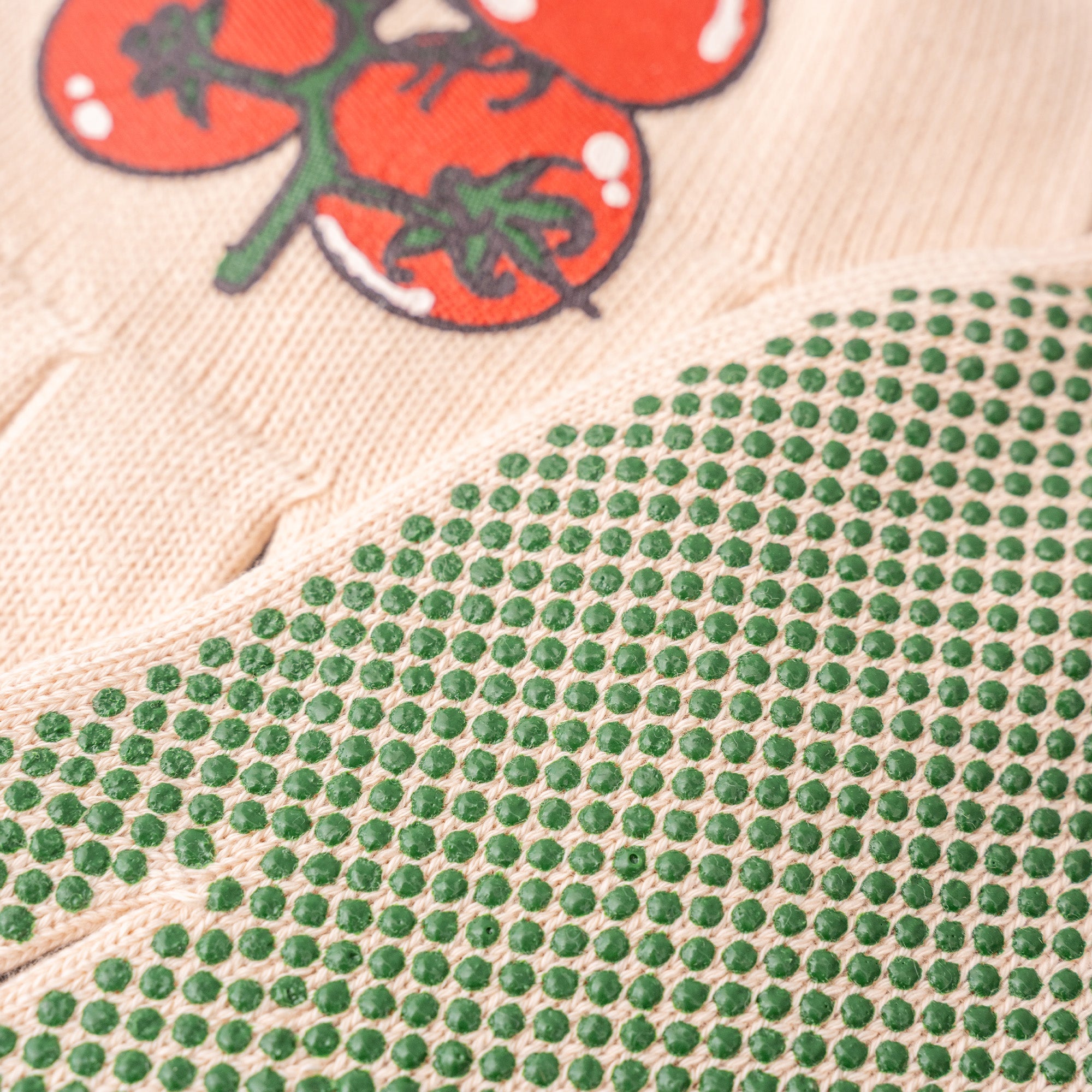 Close-up of green bead pattern on fabric with tomato illustration in the background