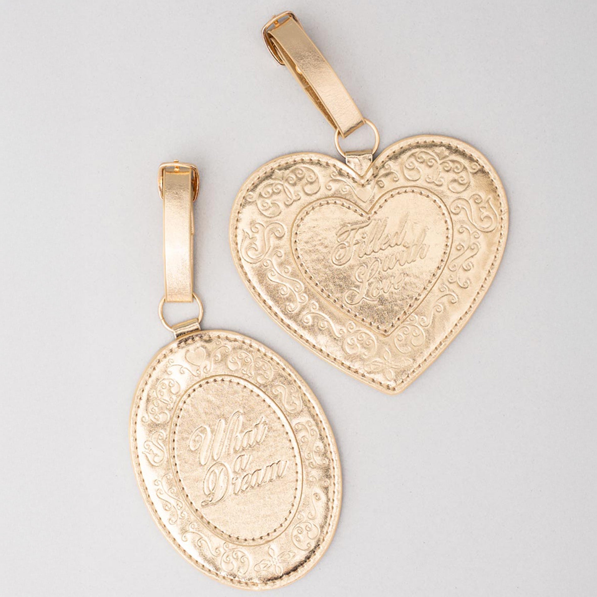 Two gold pendants with intricate designs on a light gray background