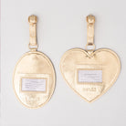 Gold heart and oval luggage tags with name labels on a light gray background