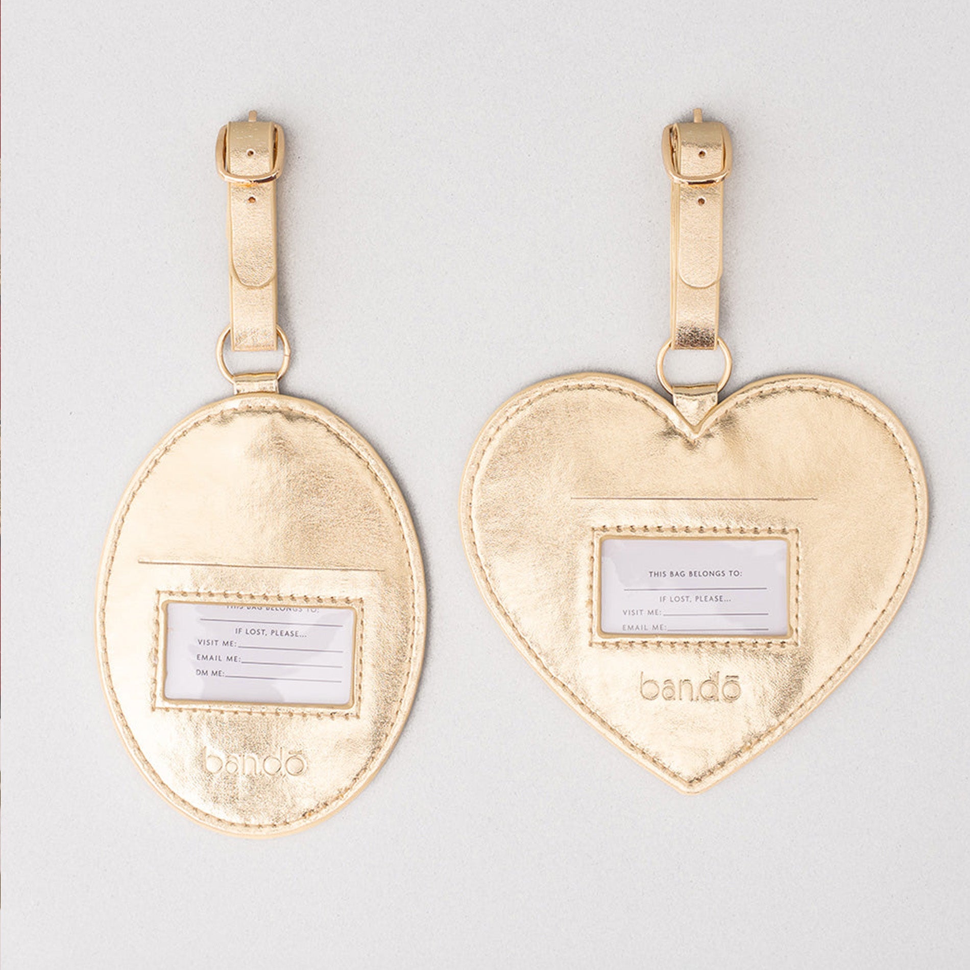 Gold heart and oval luggage tags with name labels on a light gray background