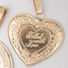Gold heart-shaped pendant with 'Filled with Love' engraving on a light gray background