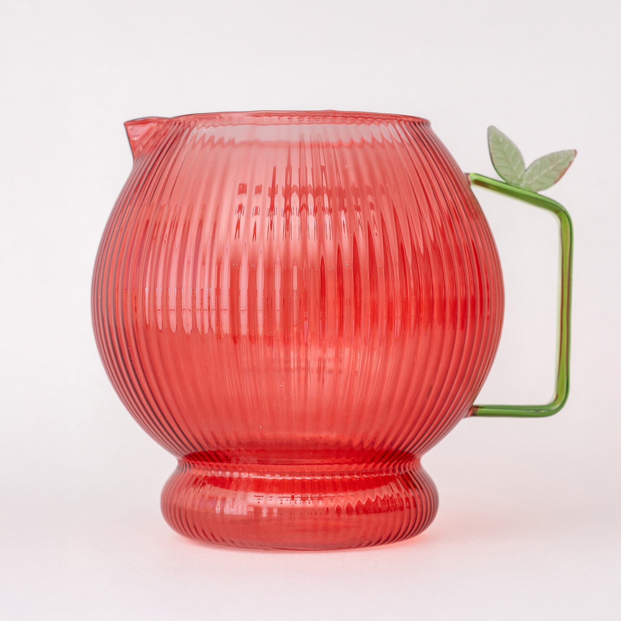 Apple glass pitcher with ribbed texture and green handle on a white background