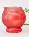 Apple glass pitcher with ribbed texture and green handle on a white background