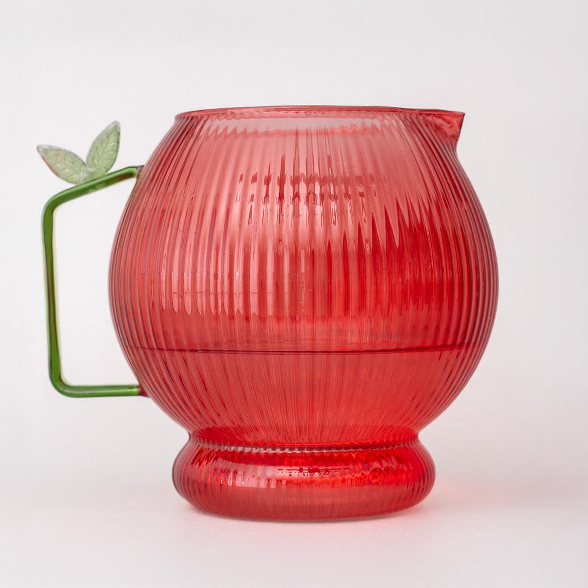 Apple glass pitcher with ribbed texture and green handle on a white background