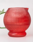 Apple glass pitcher with ribbed texture and green handle on a white background