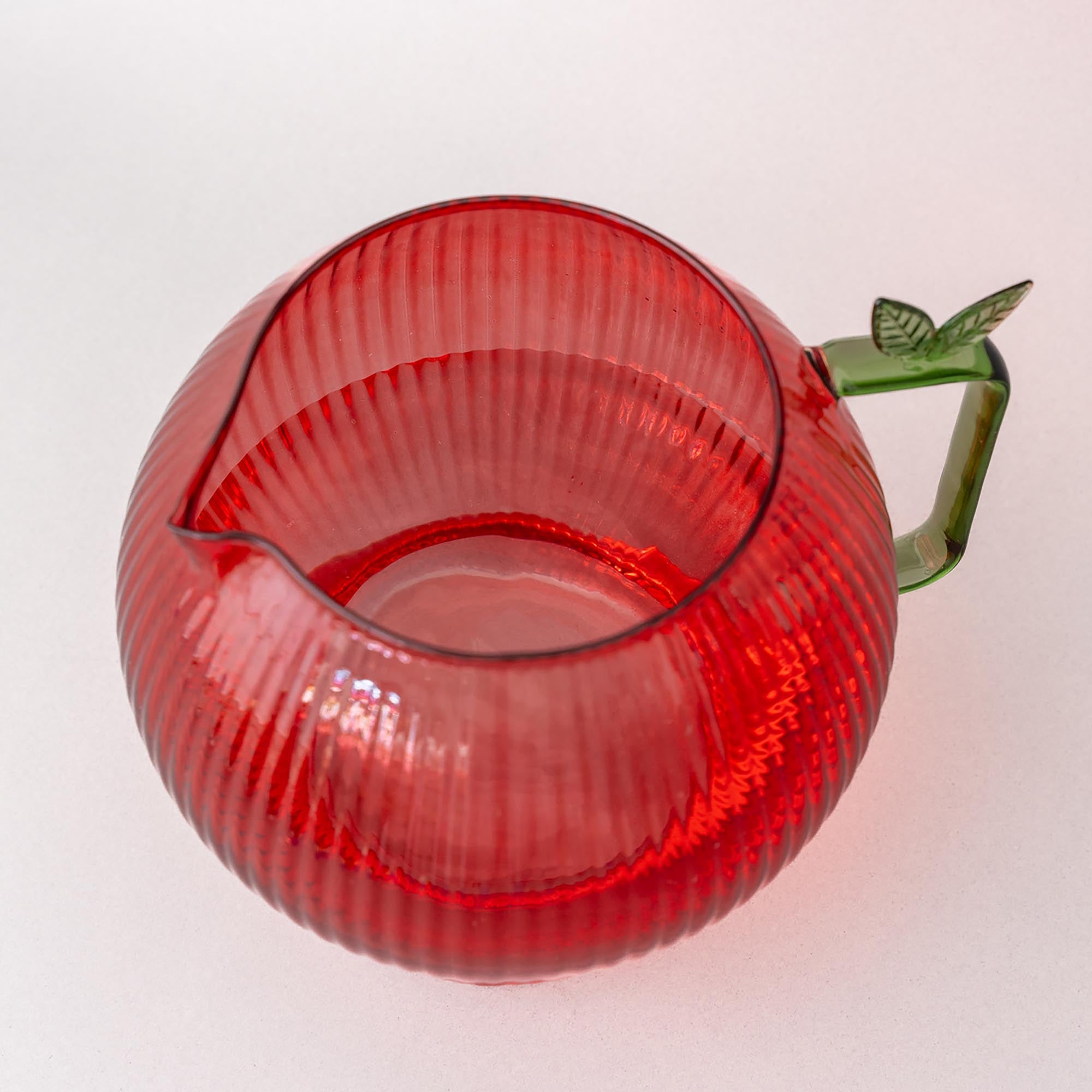 top view of Apple glass pitcher with ribbed texture and green handle on a white background