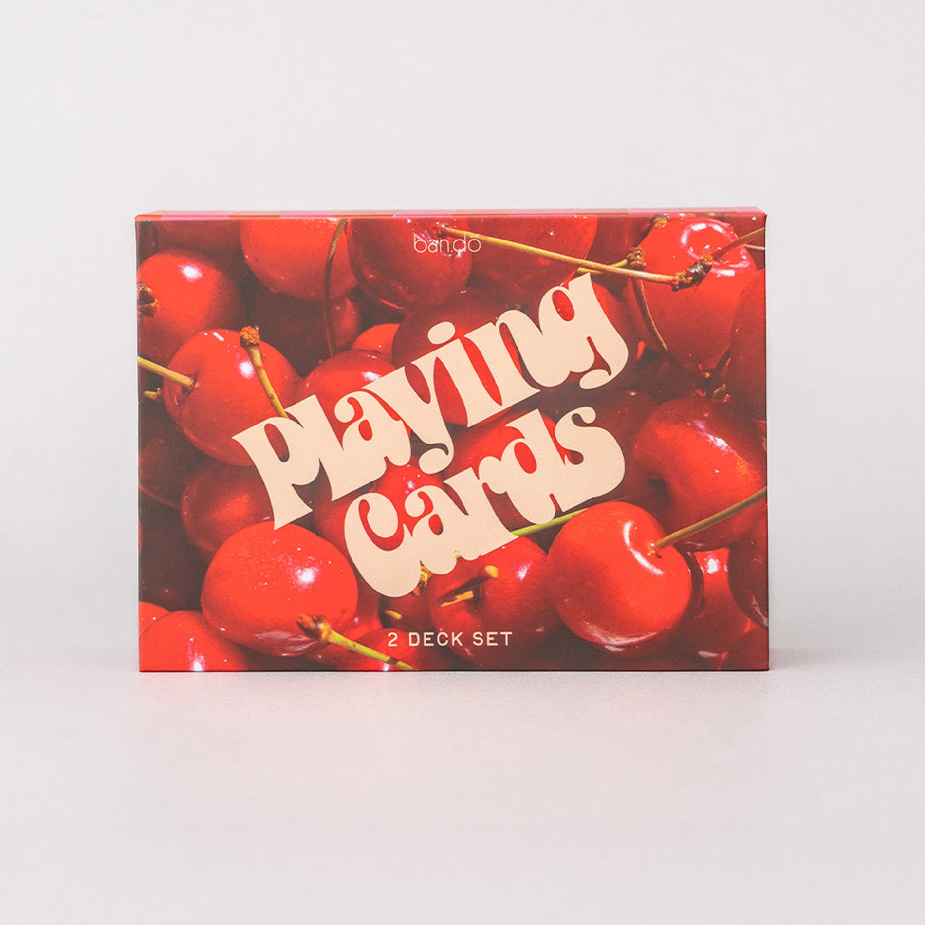 Playing card set packaging with red cherries on a white background