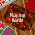 Box of playing cards with cherry design on a wooden surface