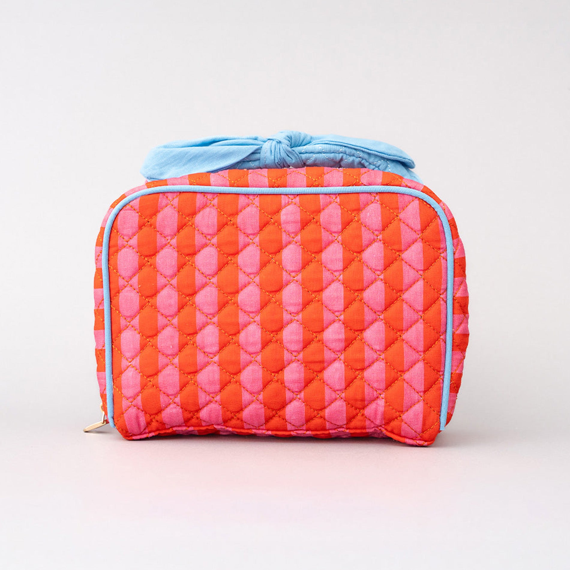 Quilted makeup bag with pink and orange pattern on a light gray background