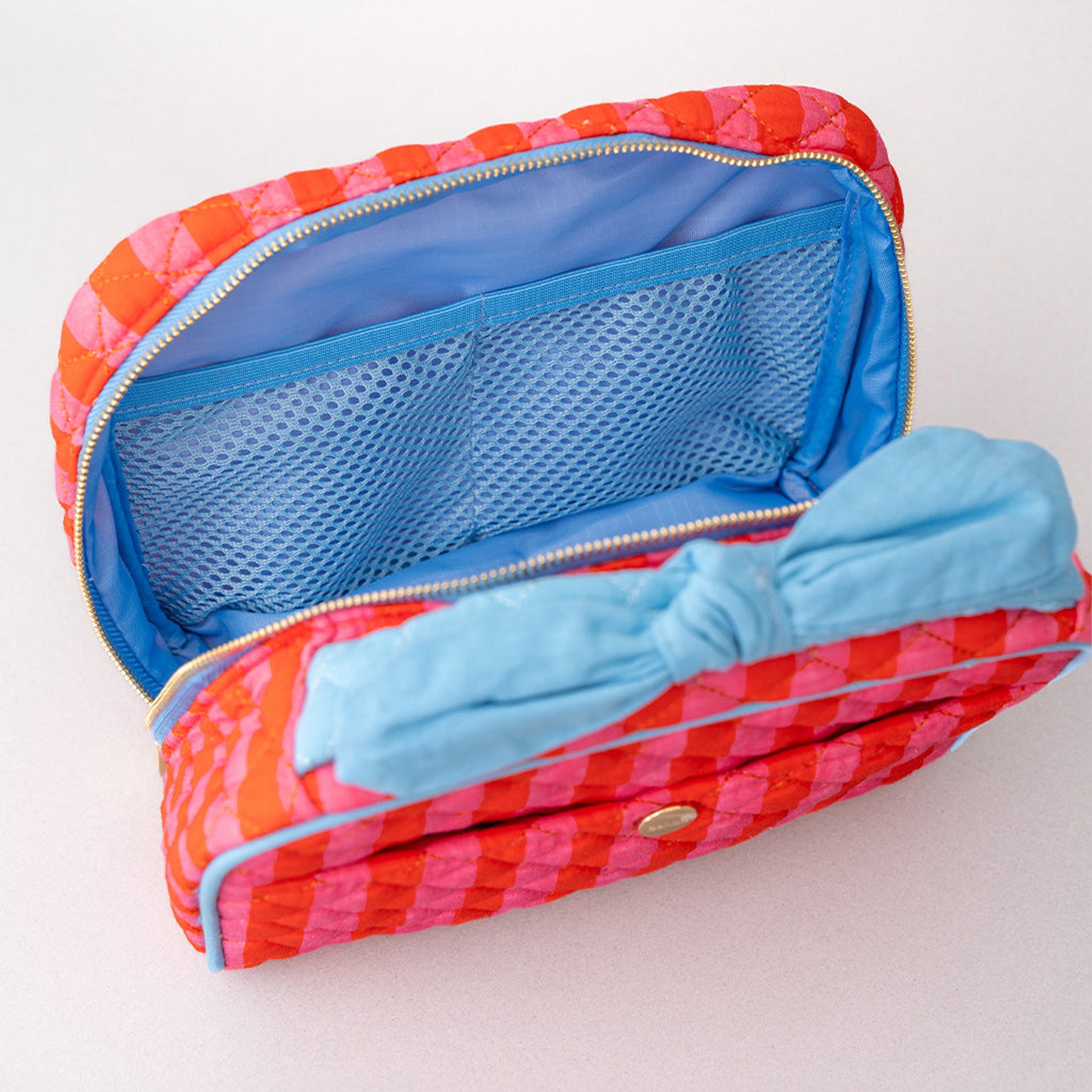Red and pink pouch with blue interior and bow on a white background