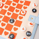 Checkered board with heart patterns and game pieces on a beige background