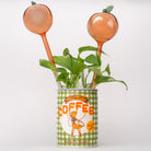 Decorative plant with peach-colored pots on top of a vintage-style coffee can.