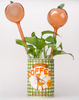 Decorative plant with peach-colored pots on top of a vintage-style coffee can.