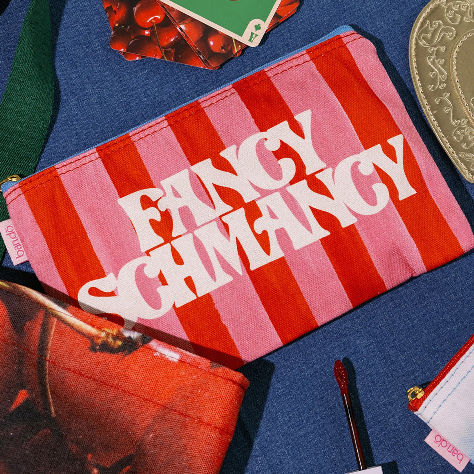 Striped pouch with 'Fancy Schmancy' text on a blue surface with accessories.