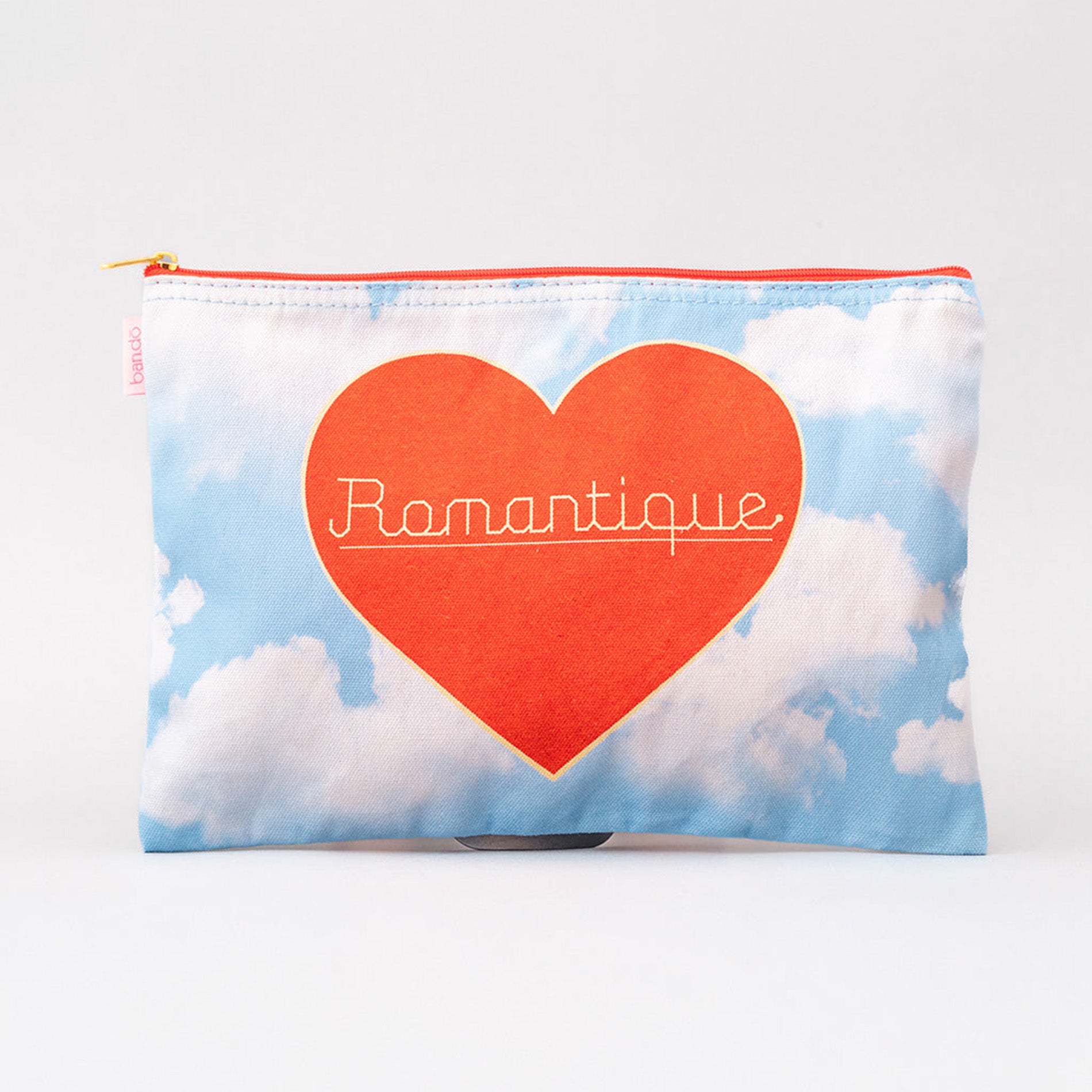 Pouch with a red heart and 'Romantique' text on a blue sky with clouds background