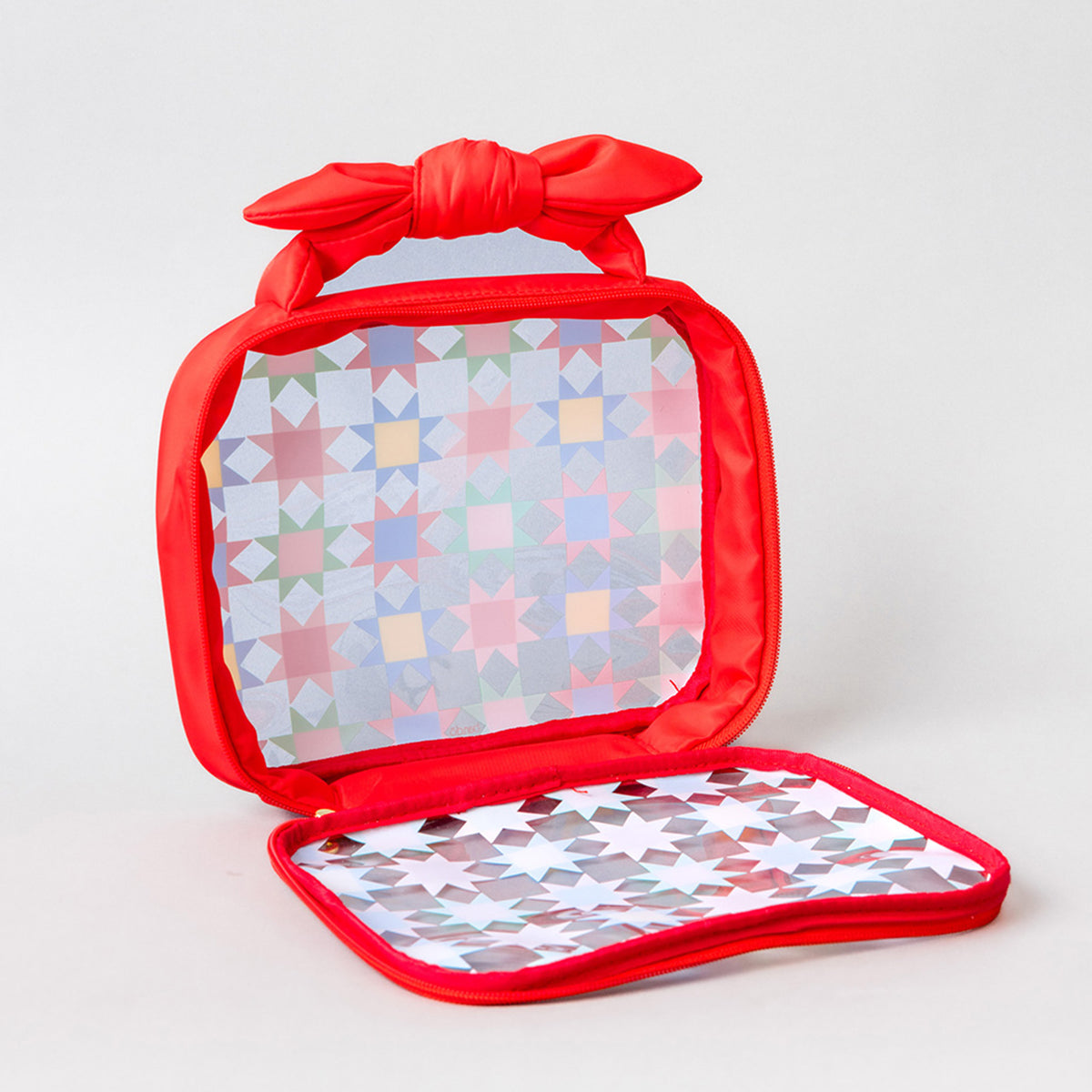 opened clear bag with red trim and bow handle with colorful quilt print