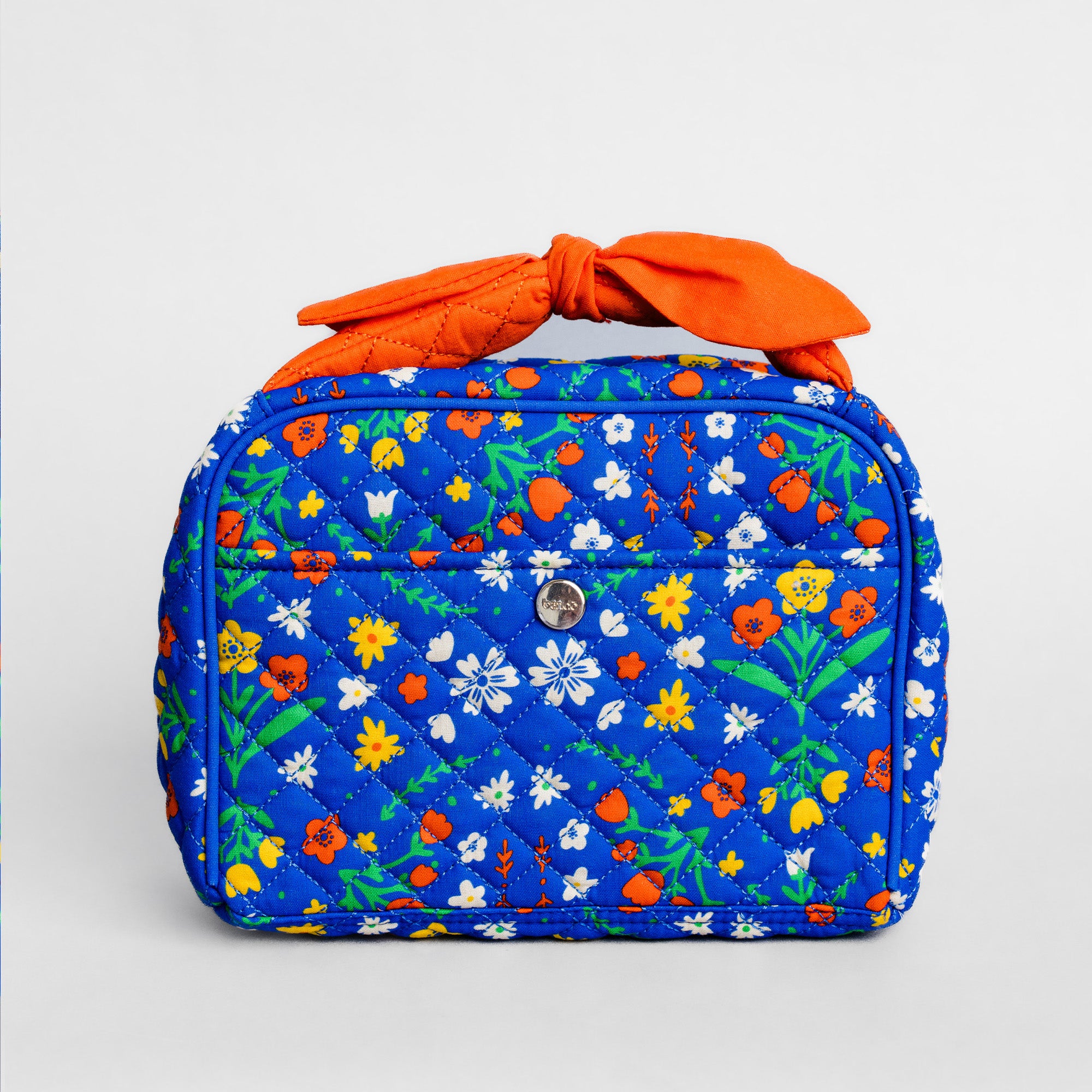 A quilted cosmetic bag in a vibrant blue floral print with a bright orange fabric handle tied in a bow, set against a plain light gray background.