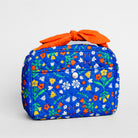 A quilted cosmetic bag with a vibrant blue background and a colorful floral print, featuring a bright orange fabric handle tied in a bow and a silver snap button on the front.