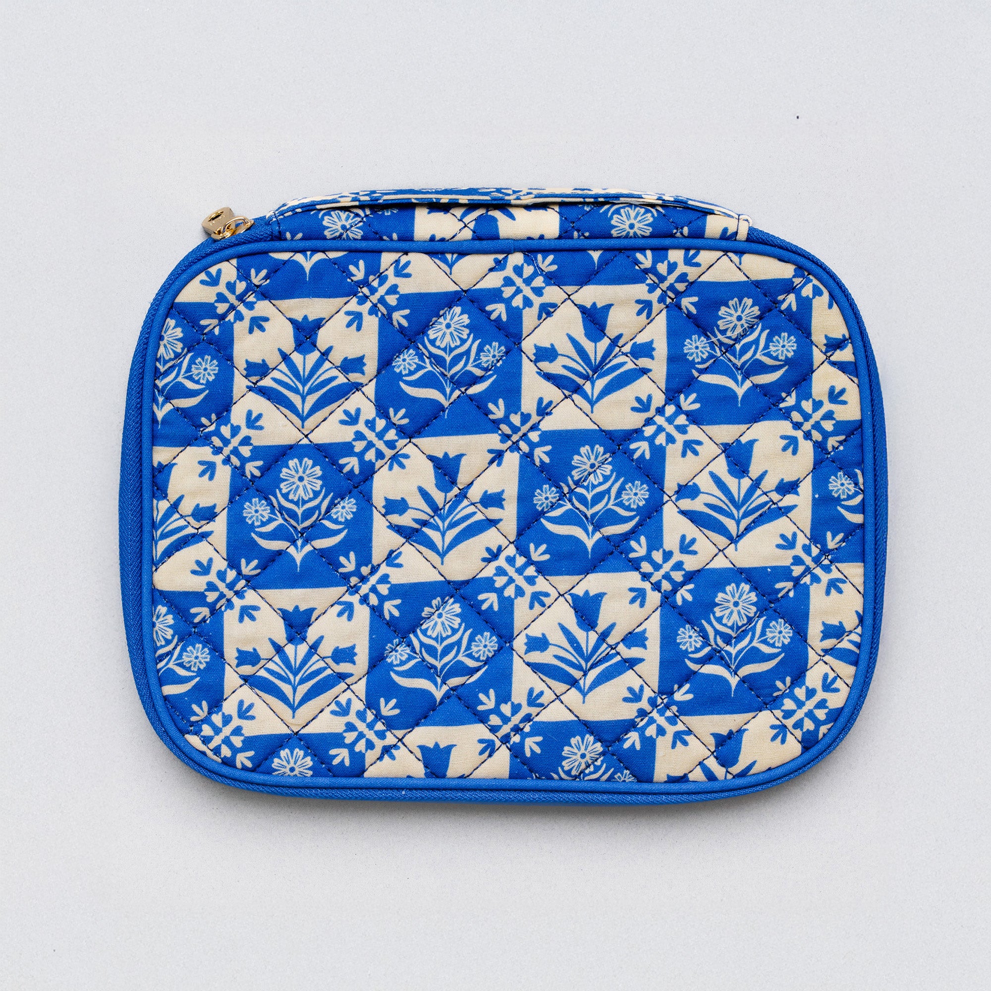 A quilted zippered pouch featuring a blue and cream floral tile pattern, photographed flat against a light gray background.