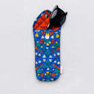 A quilted fabric sunglasses pouch with a blue floral pattern, orange quilted lining, and a snap button closure, shown on a light gray background with black sunglasses inside.