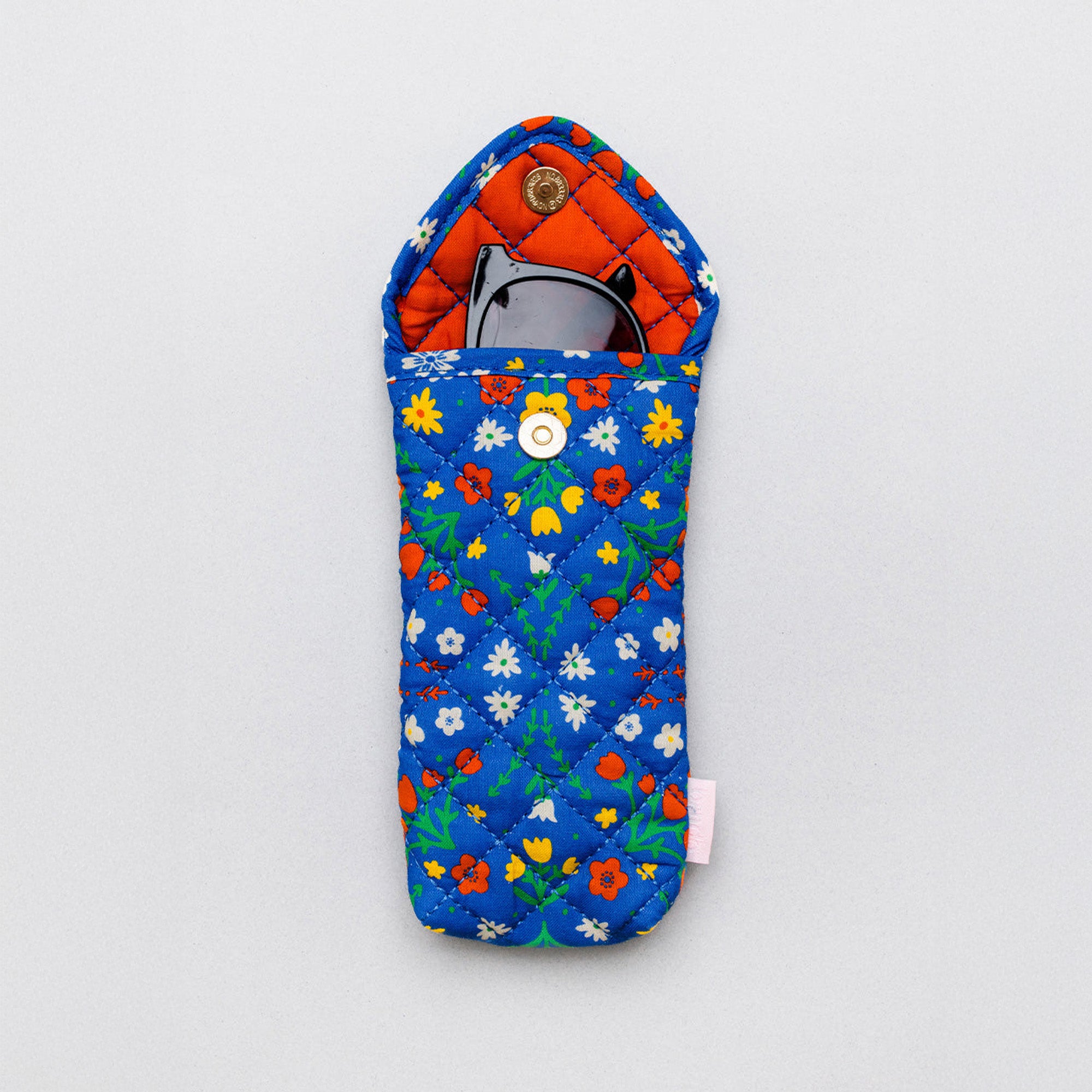A quilted fabric sunglasses case with a blue background and a colorful floral print, shown on a light gray background with sunglasses inside.