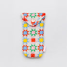 A fabric pouch with a colorful geometric star pattern on a light background, featuring a snap button closure at the top and a small pink tag on the side, photographed on a neutral light gray background.