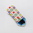 A quilted fabric pouch with a colorful geometric star pattern in red, yellow, green, blue, and pink on a white background, shown with a pair of sunglasses inside on a light gray background.