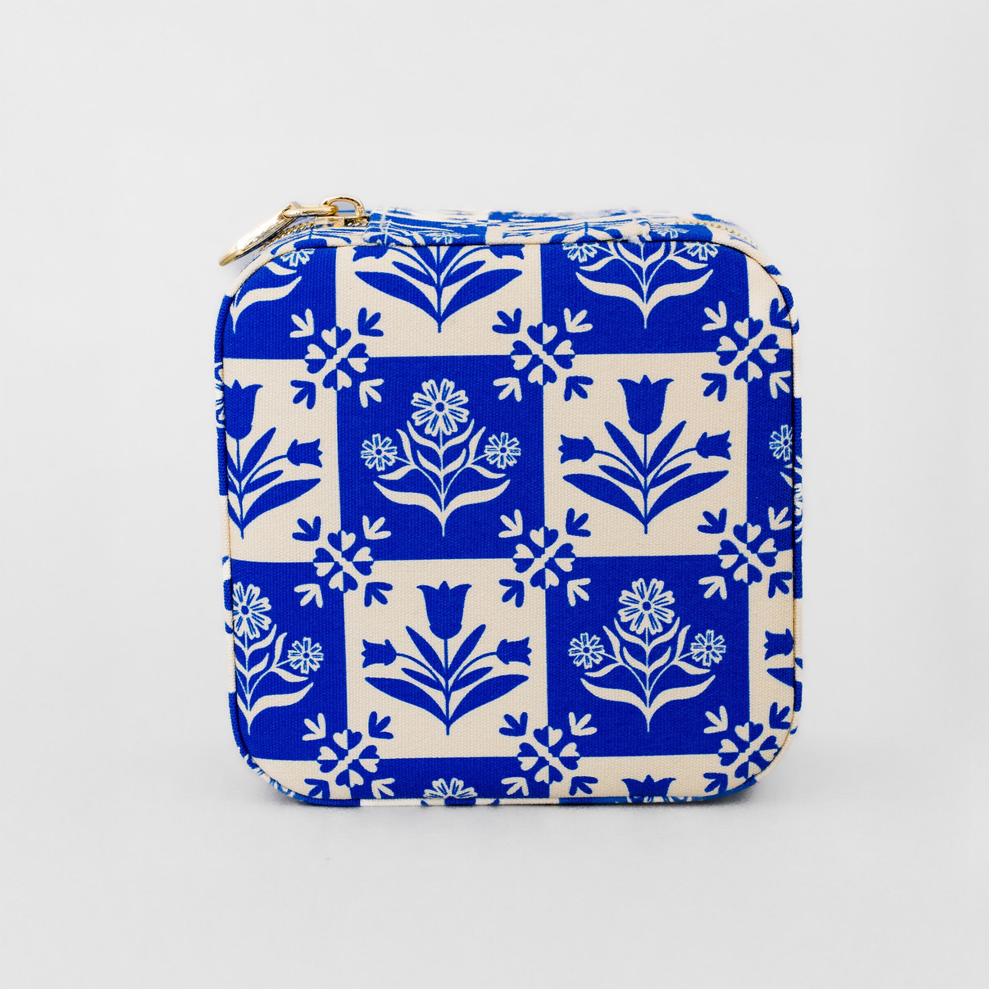 A square zippered pouch featuring a classic blue and cream floral block print pattern, with a gold zipper pull, shown against a plain light gray background.