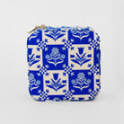 A square zippered pouch featuring a classic blue and cream floral block print pattern, with a gold zipper pull, shown against a plain light gray background.