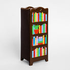 A dark brown wooden bookshelf with four shelves, decorated with colorful painted books and a small strawberry illustration, shown on a light gray background.