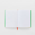 An open lined notebook with white pages, green side covers, and a small red ribbon bookmark, photographed on a clean white background.