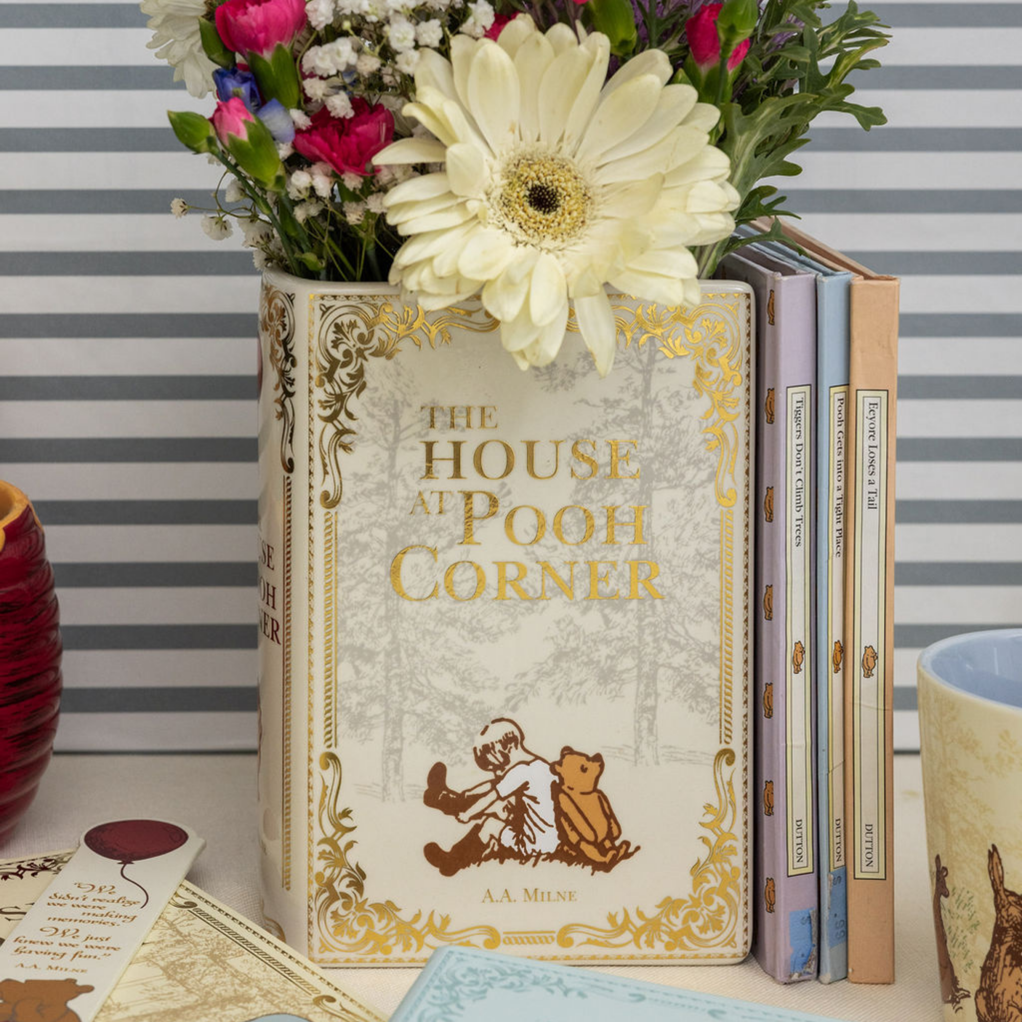 Decorative book titled 'The House at Pooh Corner' with flowers on a striped background