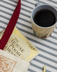 Cup of coffee next to a book titled 'The House at Pooh Corner' on a striped surface.