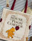 Book titled 'The House at Pooh Corner' with a bear illustration on a striped surface.