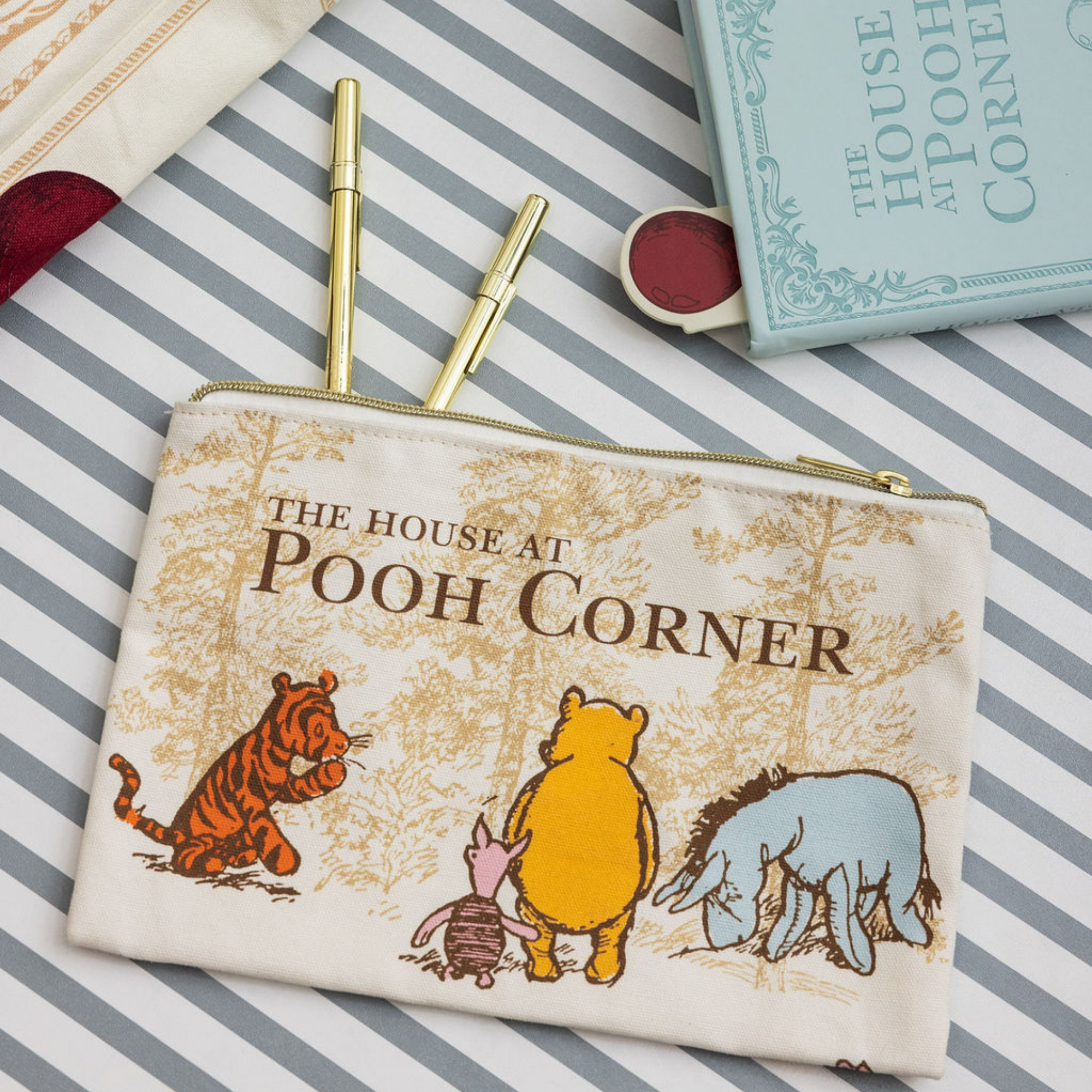 Pouch with 'The House at Pooh Corner' design featuring Pooh and friends on a striped background.