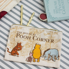 Pouch with 'The House at Pooh Corner' design featuring Pooh and friends on a striped background.