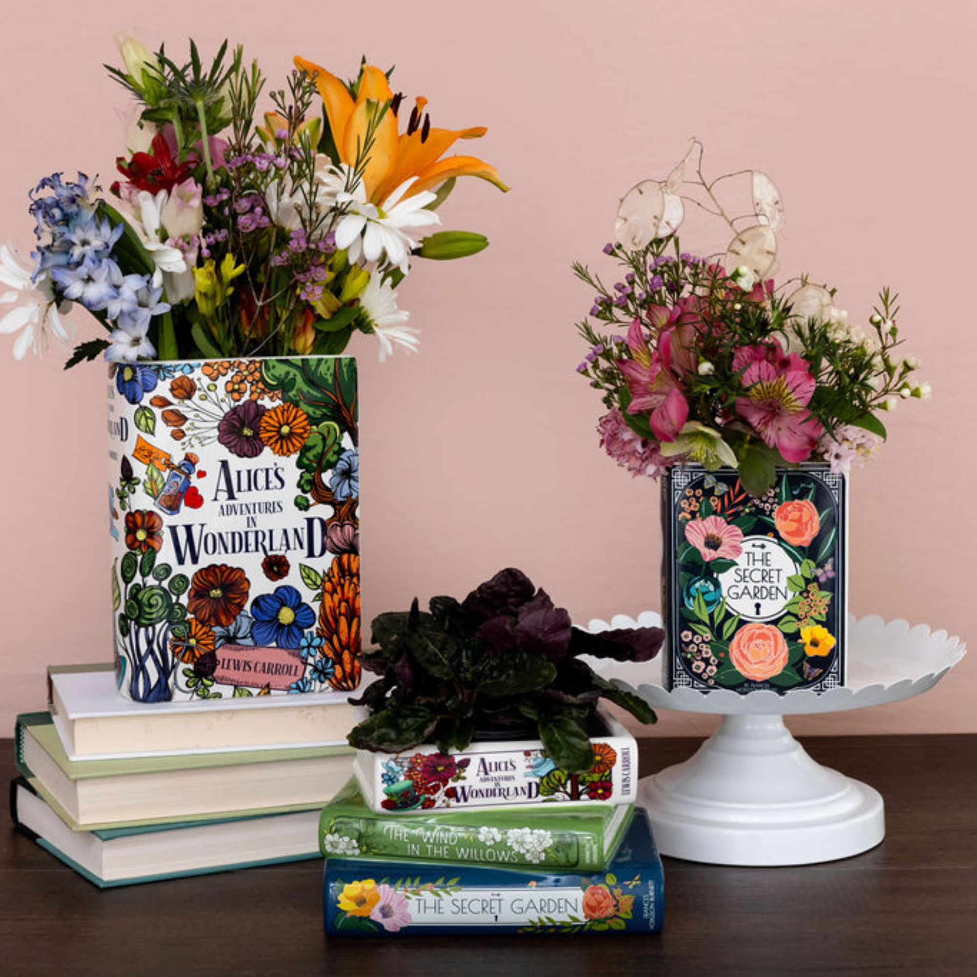 Floral arrangements in books with 'Alice's Adventures in Wonderland' and 'The Secret Garden' covers on a wooden surface.