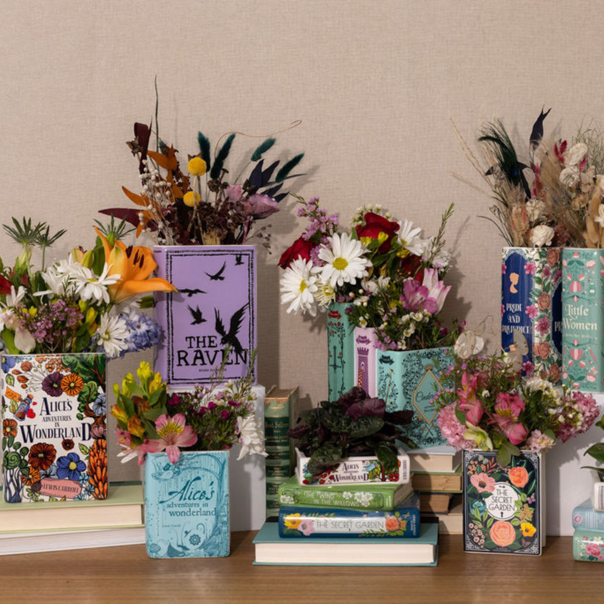 Decorative display of books and flowers on a wooden surface with a neutral background