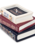 Stack of ceramic books candles with book titles on a white background