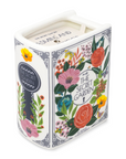 Candle in a decorative box with floral design and 'The Secret Garden' text on a white background