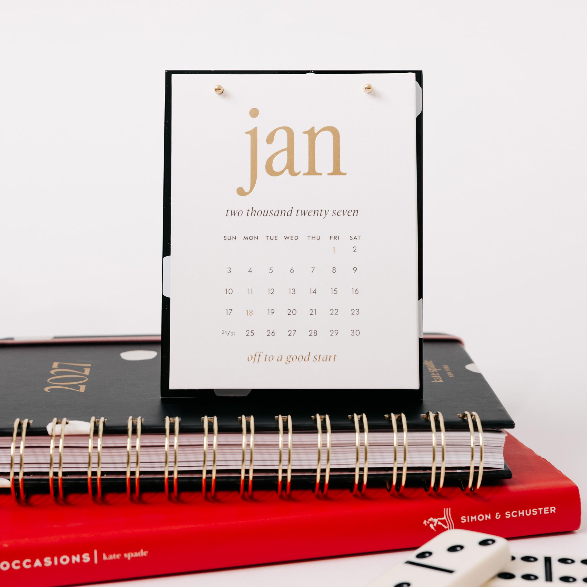 black and white polka dot acrylic desk calendar on a stack of books
