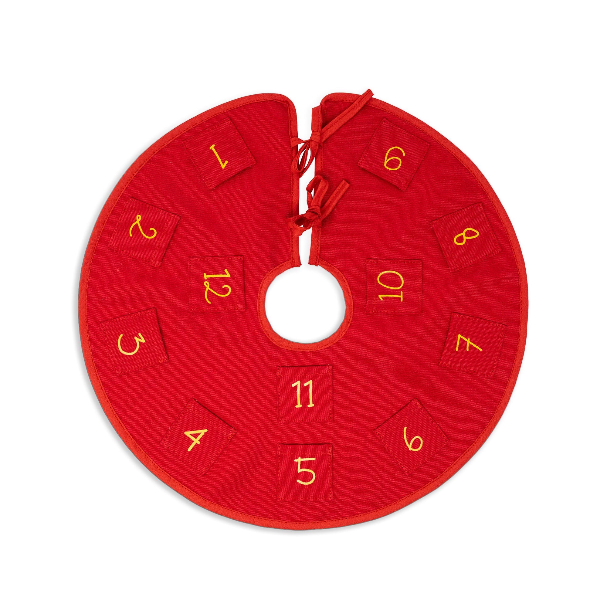 A red circular Christmas tree skirt with a central hole, featuring twelve numbered fabric squares in yellow numerals 1 through 12 around the outer edge.