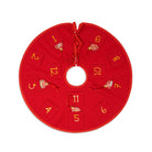 A red Christmas advent circle with ten numbered pockets (1 through 12) arranged around a central hole, each pocket decorated with a small hanging ornament, shown on a plain white background.