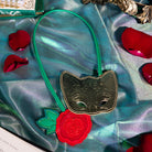 Gold mask with green strap and red rose bookmark on a silky teal cloth
