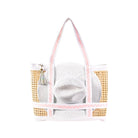 Raffia beach bag with gold accents and a white hat inside on a white background