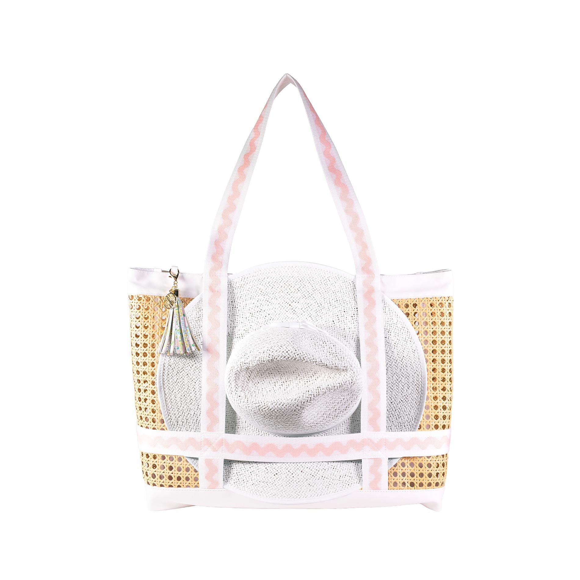 Raffia beach bag with gold accents and a white hat inside on a white background